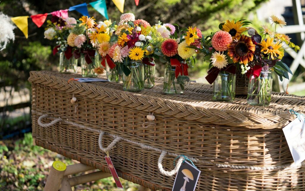 Flowers adorn a wicker coffin at a celebration.