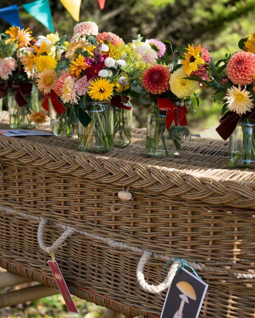 Flowers adorn a wicker coffin at a celebration.