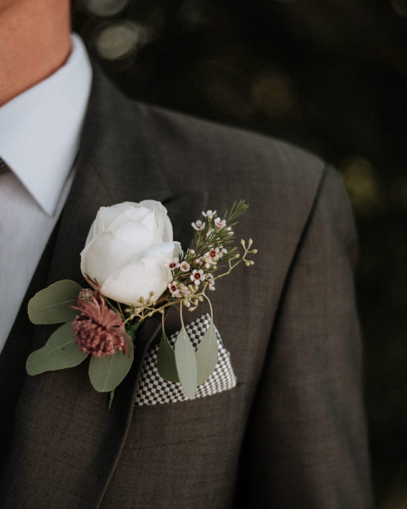 A closeup shot of a male wearing a tuxedo with a boutonniere in its pocket